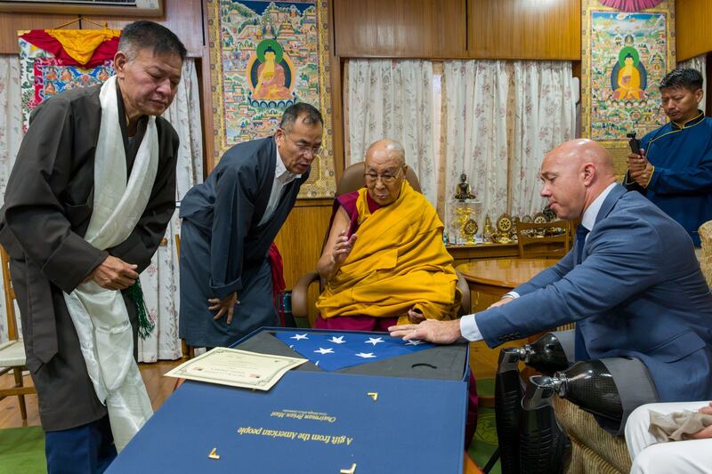 House Foreign Relations Committee Chairman Rep. Brian Mast, right, presents a U.S. flag to the Dalai Lama as Sikyong Penpa Tsering, president of the Tibetan government-in-exile, on Sept. 30, 2026, in Dharamsala, India.