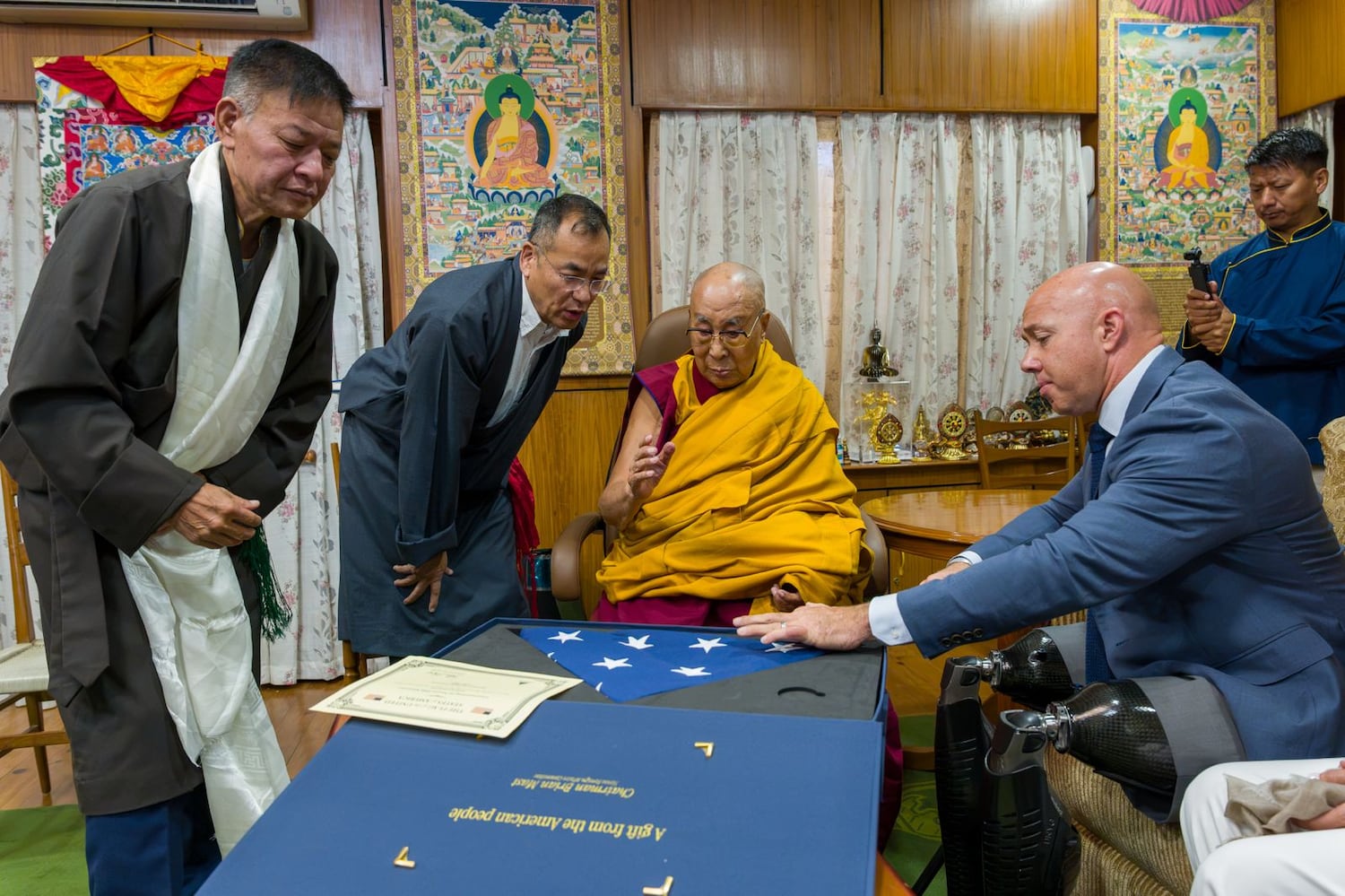 House Foreign Affairs Committee Chairman Rep. Brian Mast, right, presents a U.S. flag to the Dalai Lama as Sikyong Penpa Tsering, president of the Tibetan government-in-exile, watches on Sept. 30, 2026, in Dharamsala, India.