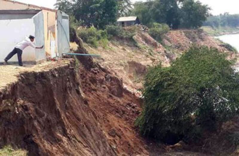 A resident of Preah Prasop commune takes a photo of the collapsed river bank, Feb. 19, 2014. Credit: RFA