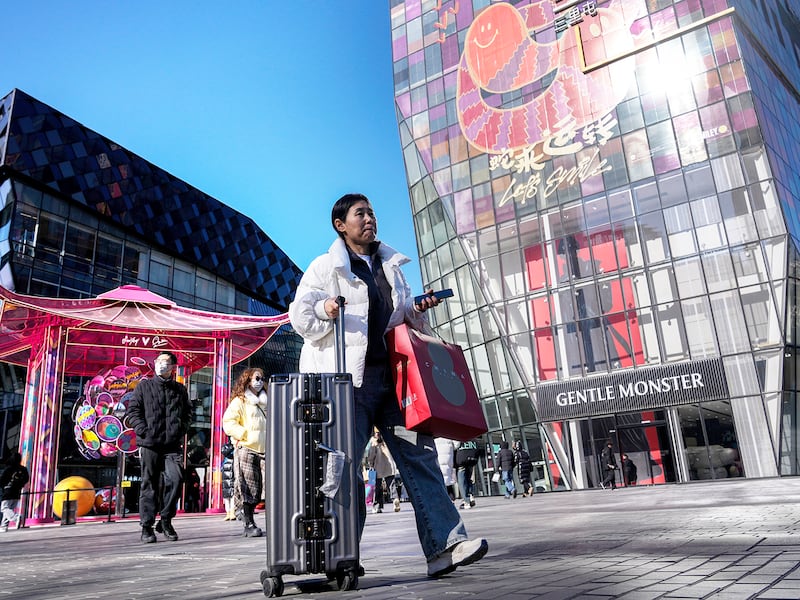 Shoppers tour by a popular outdoor shopping mall displaying Lunar New Year decorations in Beijing, Jan. 27, 2025.