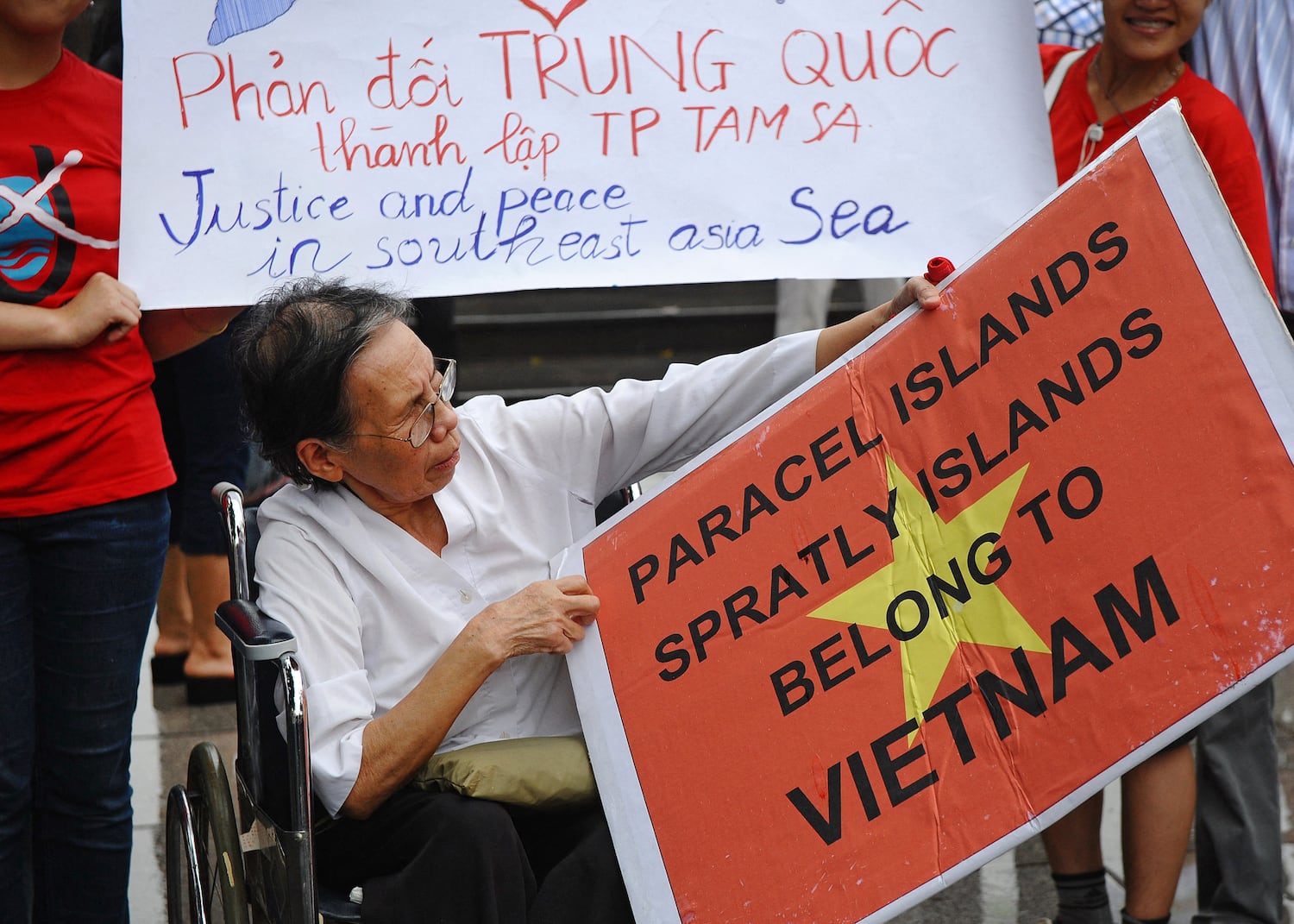 Le Hien Duc sits in her wheelchair with a placard as she joins a protest rally over the ongoing dispute in the Spratly island chain in Hanoi on July 1, 2012.