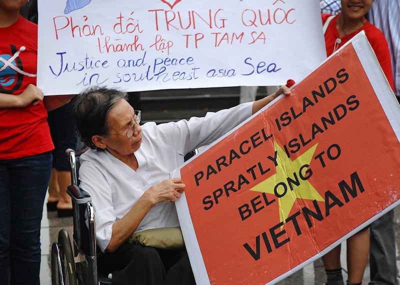Le Hien Duc sits in her wheelchair with a placard as she joins a protest rally over the ongoing dispute in the Spratly island chain in Hanoi on July 1, 2012.