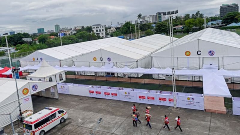 Myanmar Red Cross members walk across a parking lot at a new temporary shelter for COVID-19 patients that was set up on a soccer field in Yangon, Sept. 19, 2020. 