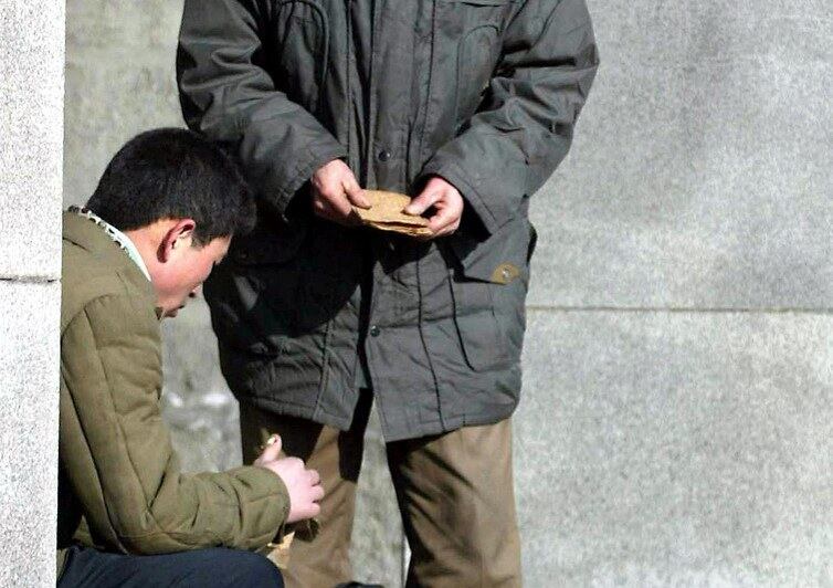 북한 남성 두 명이 평양의 한 지하철역 입구에서 암달러를 거래하고 있다.