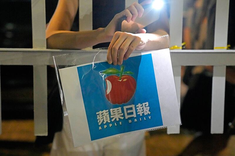 一名支持者手持最后一期《苹果日报》站在该报香港总部外(美联社)