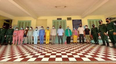 Police pose with 13 people facing charges related to the alcohol poisoning death of a dozen people in Kandal province, May 23, 2021. Kandal Provincial Police Department Facebook page